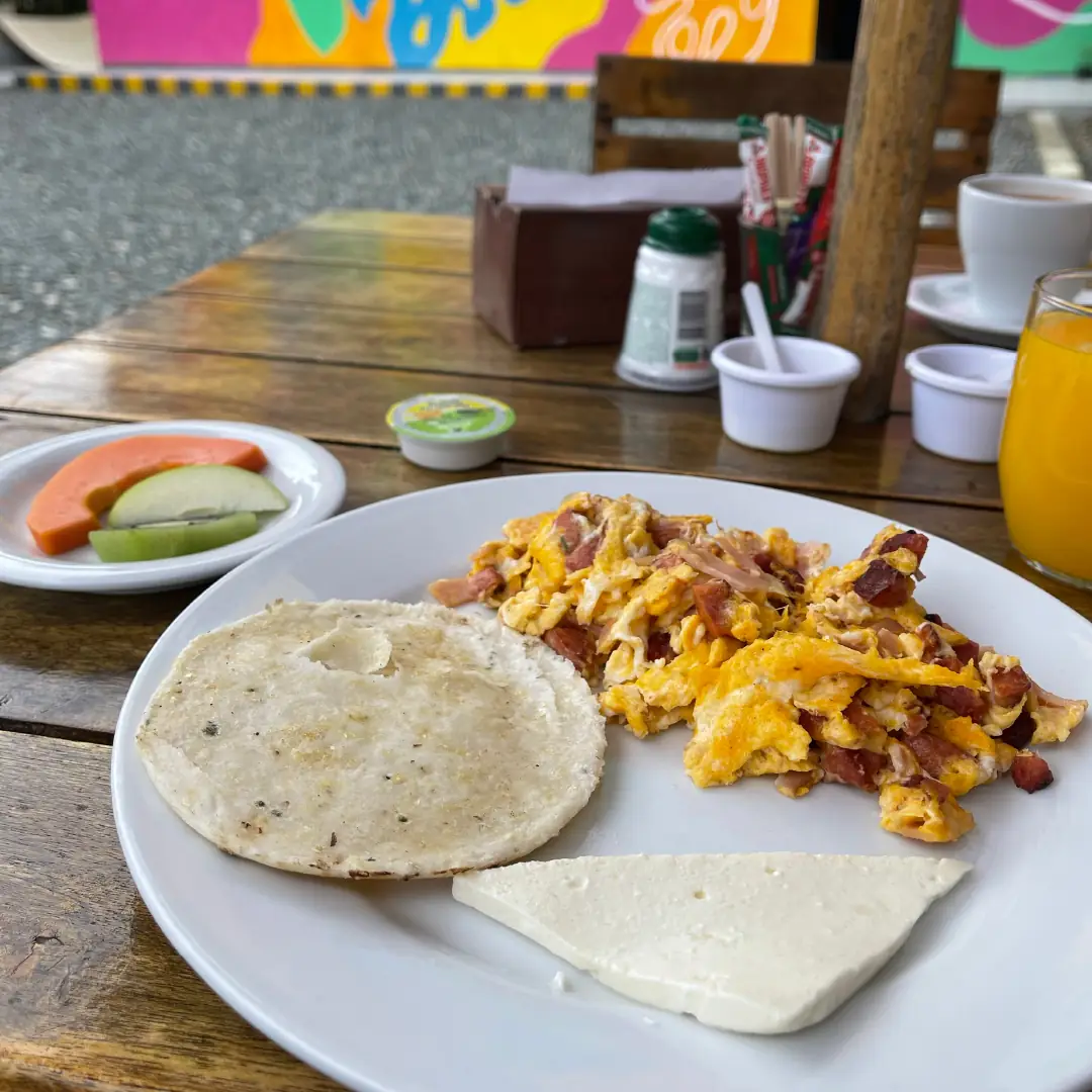 A breakfast plate with arepa, eggs and coffee.